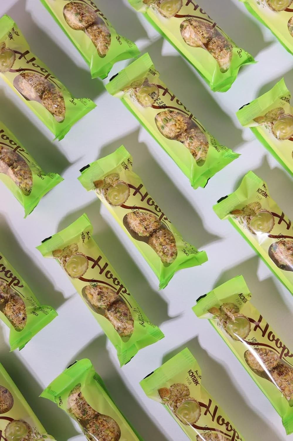 Green packaged snacks of dubai chocolate balls arranged in a grid on a white background